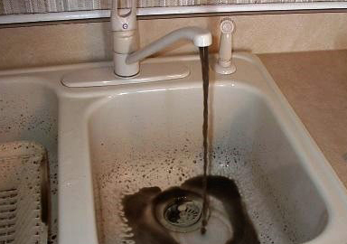 image of dirty black water coming out of a kitchen faucet
